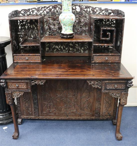 A late 19th century/early 20th century carved Chinese hardwood desk, carved in the round with bamboo flowers and foliage with possibly